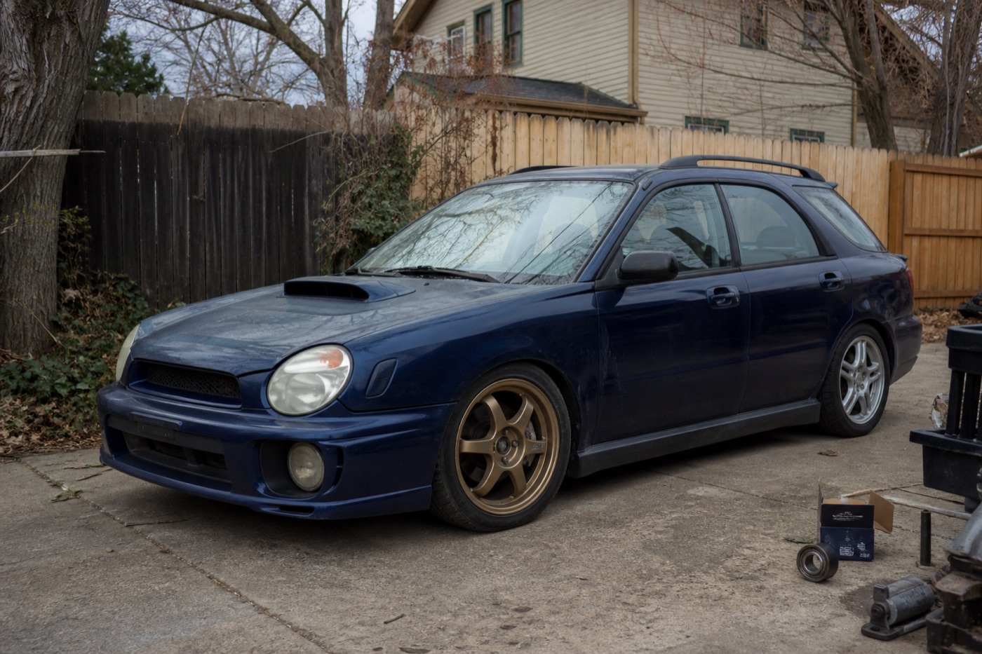 Modified dark blue 2004 Subaru WRX wagon project car in a residential driveway